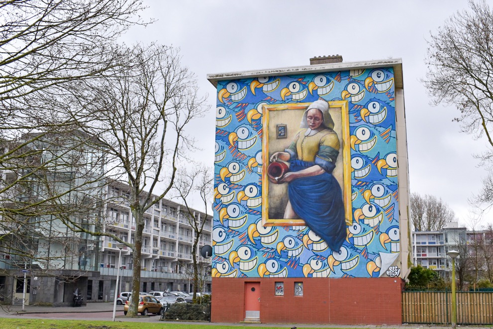 Mural of lady in Dutch traditional dress, painted on side of modern block of flats in Amsterdam suburb